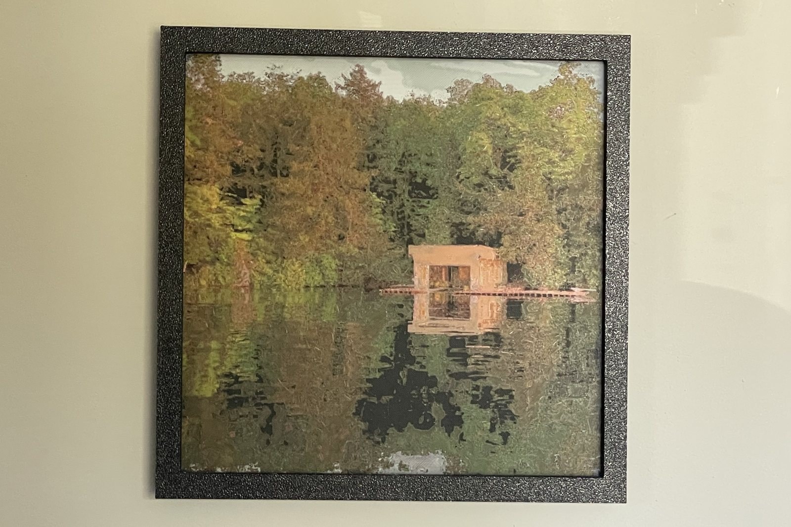 My Polychrome print of a cottage boathouse on a lake, framed on my wall