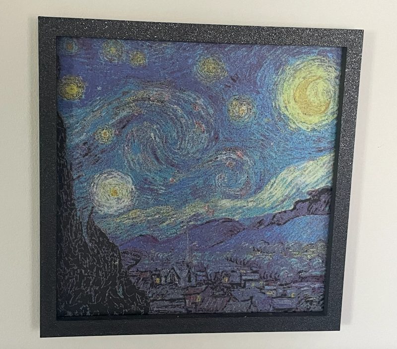 A framed Polychrome print of The Starry Night on a white wall